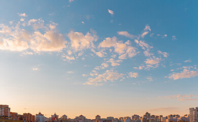 Wall Mural - Low angle view of the beautiful evening sky with light clouds over modern residential city buildings.