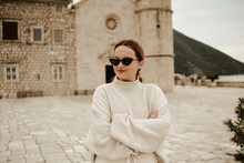 A Girl In Sunglasses And A White Suit Walks On The Island. Travel, Montenegro. Boka Island Church Of Our Lady Of The Rocks Kotor Bay.