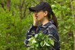 Tired woman yawning and covering open mouth with hand, need rest. Walking in green forest and being sleepy head.