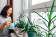© Elena - household chores. a woman is watering homemade flowers. at home