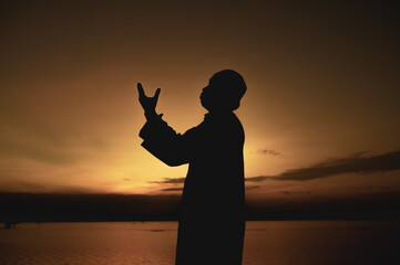 Silhouette Young asian muslim man praying on sunset,Ramadan festival concept