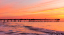 Dramatic Pastel Colors Of The Summer Morning Sky As The Waves Of The Atlantic Waters Rush In The Shores And Pier Of Virginia Beach.