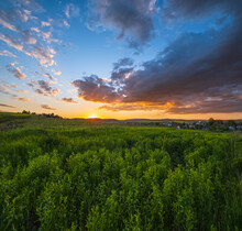 Summer Countryside Meadow, Cloudy Evening Sunset Sky, Rural Hills, Village And Fields In Far.