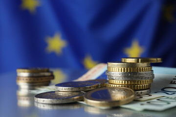 Coins and banknotes on table against European Union flag, closeup. Space for text