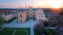 Aerial, over the garden view of Lednice Castle, Moravia, Czechia. Famous tourist spot. Fairytale castle in a baroque garden, lit by the morning sun. UNESCO cultural heritage.