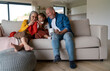© Halfpoint - Little girl sitting on sofa with her grandparents and learning to knit indoors at home.
