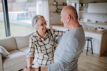 Wall Mural - Cheerful senior couple dancing together at home.