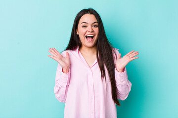 Wall Mural - young adult woman looking happy and excited, shocked with an unexpected surprise with both hands open next to face
