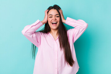 Wall Mural - young adult woman raising hands to head, open-mouthed, feeling extremely lucky, surprised, excited and happy