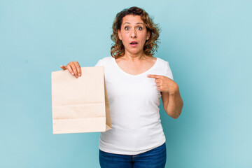 Wall Mural - middle age woman looking shocked and surprised with mouth wide open, pointing to self. take away concept