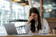 © crizzystudio - Portrait of a tired young businesswoman suffering from headache in the front laptop at office desk Overworked businesswoman suffering from headache