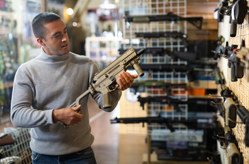 Wall Mural - Man chooses semi-automatic pneumatic assault rifle at a gun store