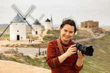 Smiling Woman Photographer Capturing With Camera Scenic Views Of Consuegra Rural Landscape With Medieval Windmills On Spring Day..