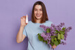 © sementsova321 - Portrait of happy healthy woman wearing T-shirt posing isolated over purple background, standing and holding nasal spray and bouquet of lilac, to treat her allergy.