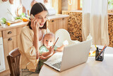 Fototapeta  - A young freelance mom works from home, in the kitchen.