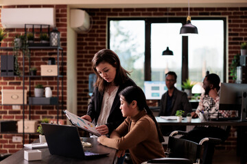Wall Mural - Diverse team of women analyzing documents report at job in disability friendly office, working together with paralyzed employee. Wheelchair user with chronic health condition doing teamwork.