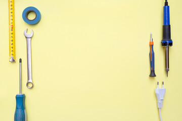 Wall Mural - Repair tools on a yellow background. Measuring tape, screwdriver, soldering iron. Place for text. Copy space. Flat lay. Top view. Handyman tool kit. DIY. Advertising for the store.