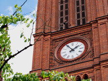 Church Clock. Red Brick Church Tower With Ancient Black And White Clock-face. Sunny Day With Blue Sky And Few Clouds.