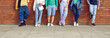 © Studio Romantic - Diverse group of people in casual clothes. Six young multiethnic men and women in trendy jeans, shorts, and trainers leaning on brick wall in street. Cropped shot, human legs, street fashion banner