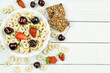 A bowl with oatmeal (corn) rings with cherry and strawberry berries on a white wooden background. A place for the text, a recipe. Dry healthy breakfast, add milk.