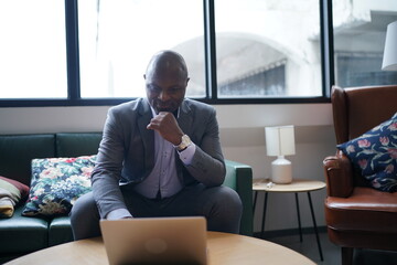 Portrai of African American businessman using  laptop of mobile device  in modern office.