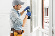© Angelov - The worker installing and checking window in the house