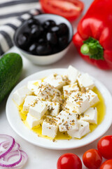 Wall Mural - Mediterranean salad food ingredients, feta cheese marinated in olive oil and oregano, black olives, red bell pepper tomatoes and onion