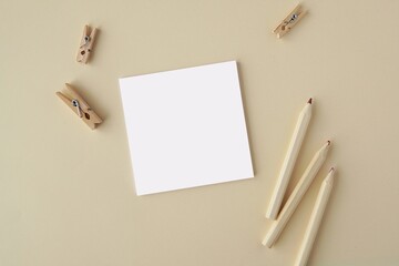 Wall Mural - Square sticky notes, note paper or notepad mockup for design or text presentation, neutral beige color background with wooden clips and pencils.