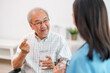 © Chatchawal - Female caregiver giving the medicine to her older male patient.