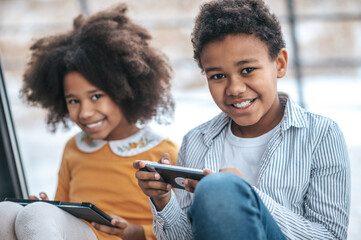 Wall Mural - Two kids spending time online using their devices