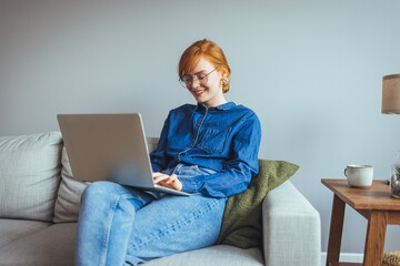 Happy businesswoman professional worker working online doing job on laptop at sofa, smiling female employee executive typing message using corporate computer software for business in modern office