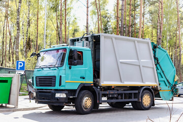 Fototapete - A garbage truck picks up garbage in a residential area. Loading mussar in containers into the car. Separate collection and disposal of garbage. Garbage collection vehicle.