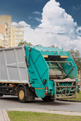 Fototapete - A garbage truck picks up garbage in a residential area. Loading mussar in containers into the car. Separate collection and disposal of garbage. Garbage collection vehicle.