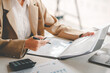 © Daenin - business woman or accountant who are using a calculator to calculate business data Accounting documents and laptop computer at the office business idea