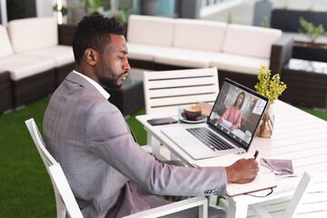 Wall Mural - African american businessman planning work while video chatting with businesswoman on laptop