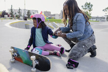 Mother Checking Daughter's Injured Wrist In Skatepark