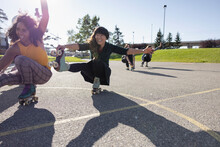 Multiethnic Friends Learning Dance On Rollerskates In Skatepark