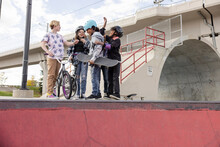 Multiethnic Skaters Chatting On Edge Of Skatebowl
