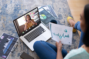 Poster - Biracial businesswoman on video call with biracial female colleague holding data while working