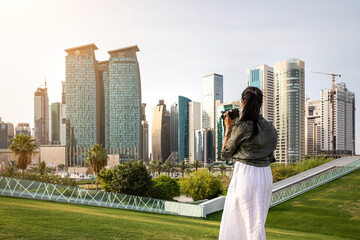 Female tourist making photos of the skyline of Doha, Qatar, during sunset time in the park