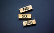 Paid sick leave symbol. Concept words Paid sick leave on wooden blocks. Beautiful black table black background. Business medical and paid sick leave concept. Copy space.