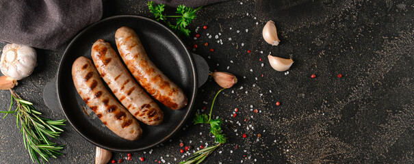 Wall Mural - Frying pan with delicious grilled sausages and spices on dark background with space for text