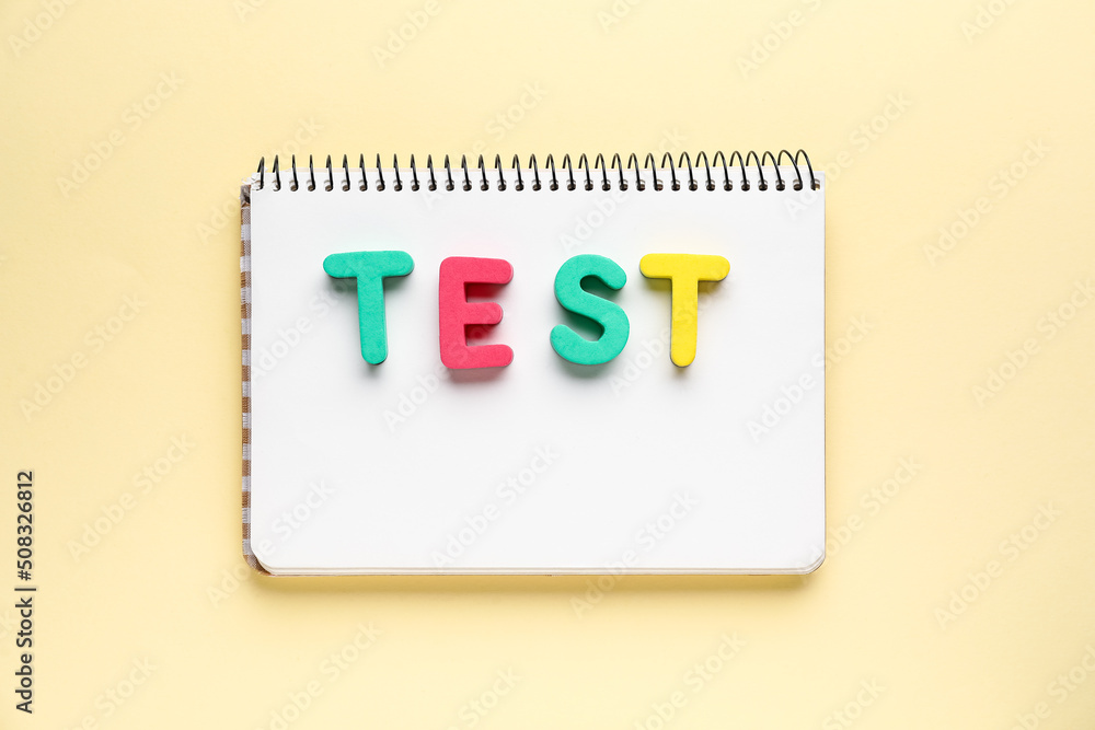 Notebook with word TEST on beige background