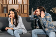 © Kateryna - Clarification of relations between spouses. Caucasian couple sitting on sofa in living room, quarreling over disagreement, man yelling at woman, woman experiencing psychological abuse from her husband