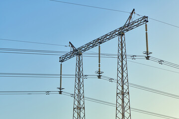 High voltage electricity tower with power line against blue sky. Overhead electric power line with insulators. Electricity generation, transmission, and distribution network. Indastry landscape.