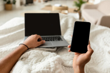 Wall Mural - POV Of Man Using Smartphone And Laptop In Bedroom, Cropped