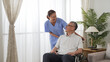 © PRPicturesProduction - Friendly taiwanese woman nursing aide putting hands on disabled grandfather’s shoulders while talking to him at home. he sits on a wheelchair and has smile on face