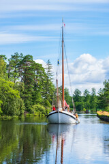 Poster - Wooden old sailboat in a canal in a beautiful landscape