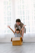 Happy Asian family have a fun spend time at home. Portrait of father and adorable daughter pushing cardboard box around living room in junk modelled car. Real estate, purchase, Family concept.