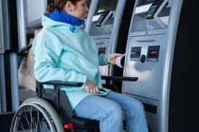 Caucasian Woman In A Wheelchair Buys A Ticket At A Self-service Ticket Office. 